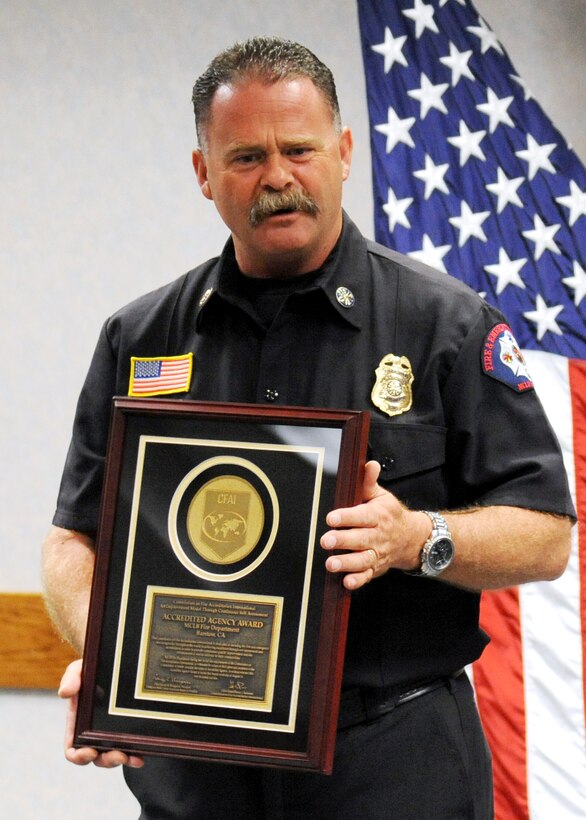Tommy Thompson, fire chief, Marine Corps Fire Department, Marine Corps Logistics Base Barstow, Calif., poses with his Fire and Emergency Service Accreditation Award.